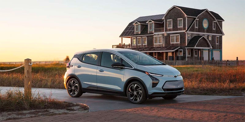 2023 Chevrolet Bolt EV parked on a driveway with a house in the background