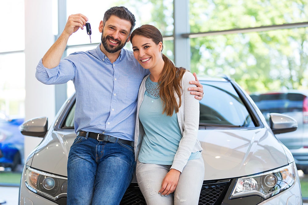 Couple holding car keys at dealership